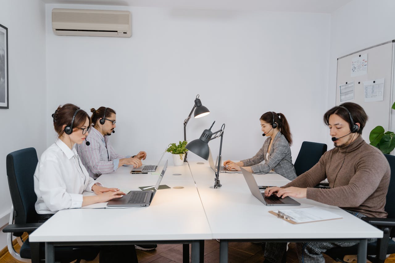 about-01 A diverse group of professionals working on laptops in a modern call center office.